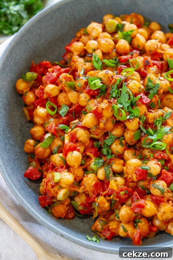 looking down into a large blue bowl filled with chickpeas cooked with tomatoes and spices.