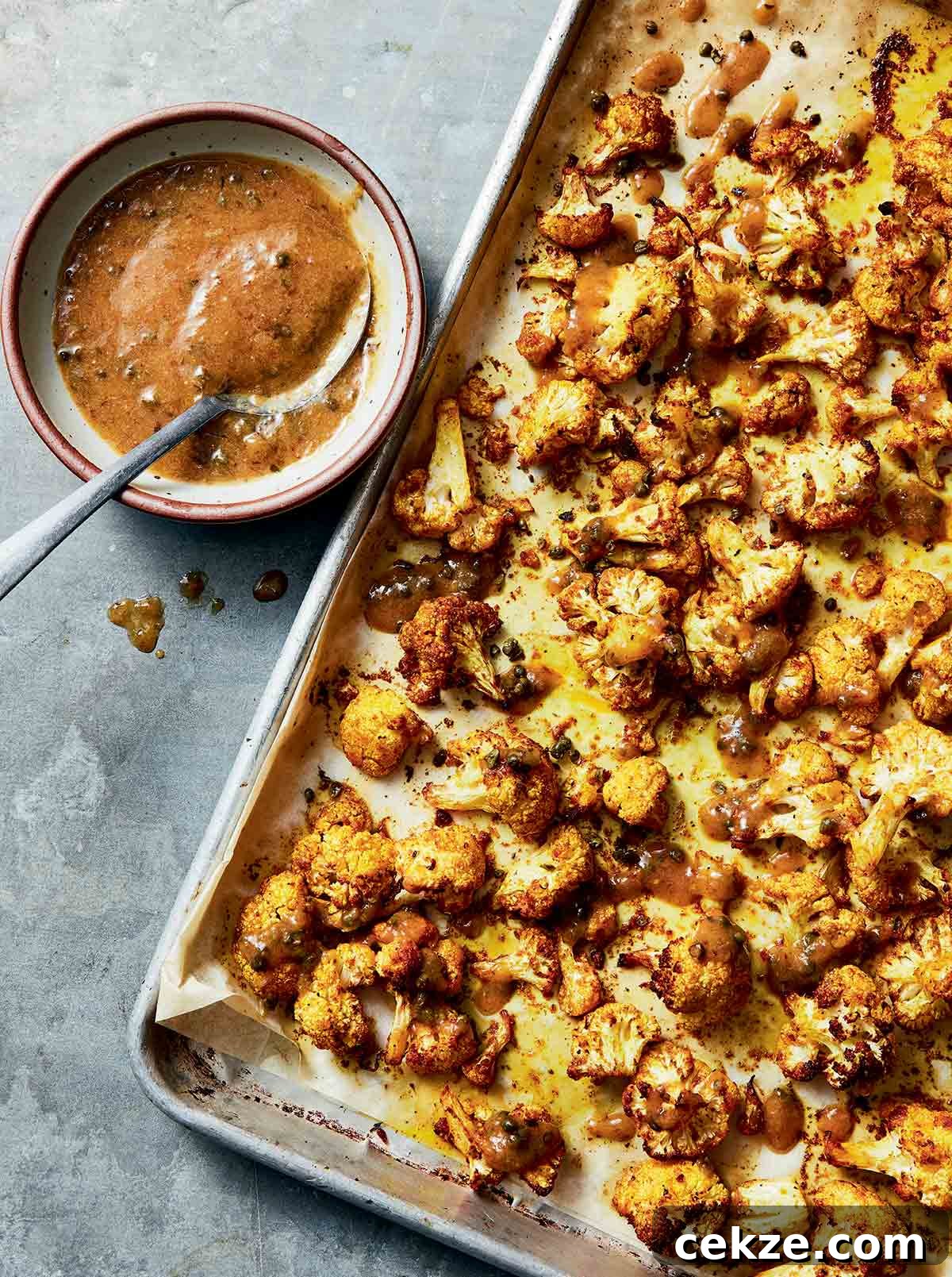 Crispy Spicy Roasted Cauliflower with Chili and Garlic 10 Sicilian-style roasted cauliflower on a sheet pan with a bowl of dressing.