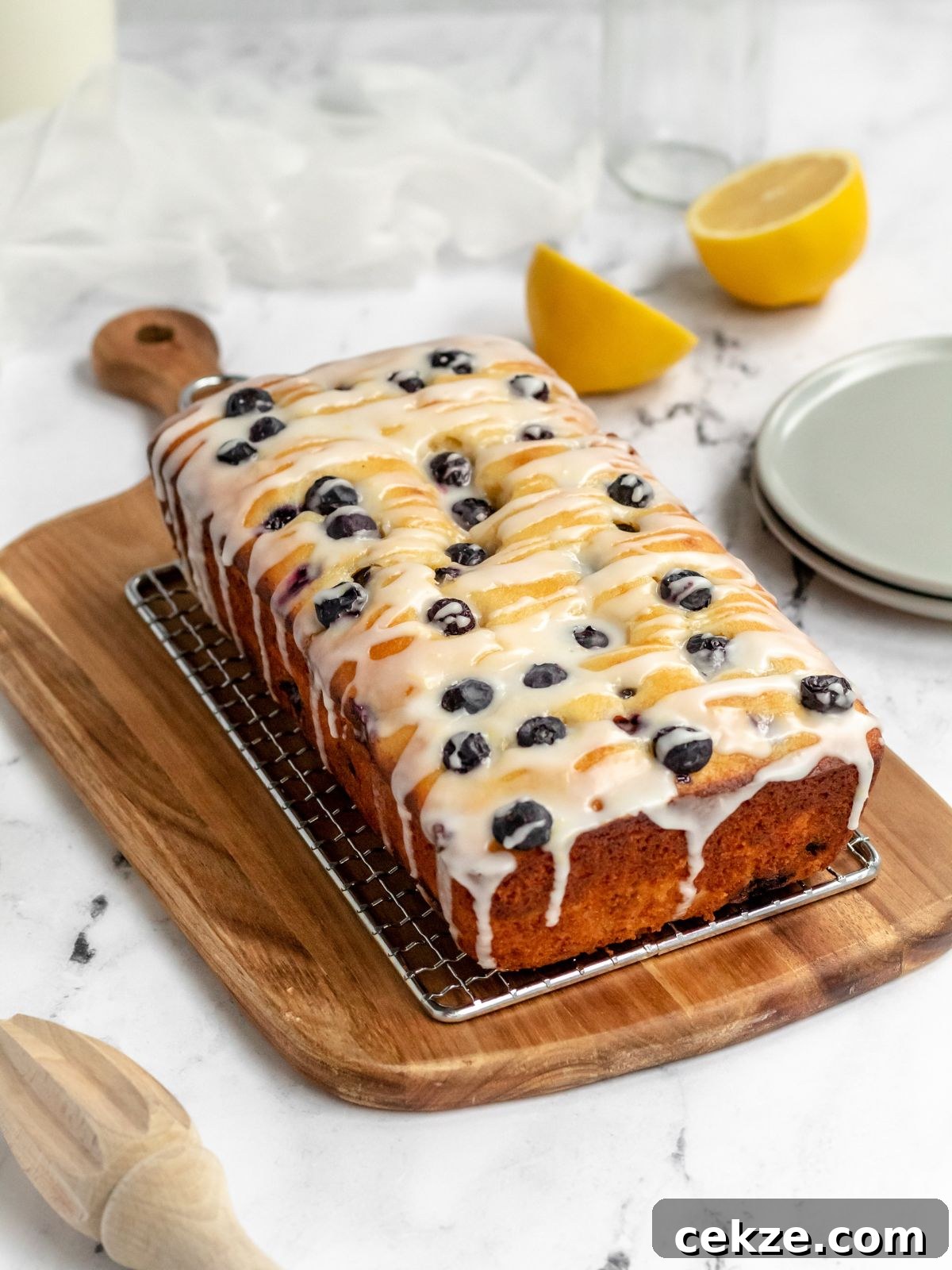 Blueberry loaf cake drizzled with icing on a rack.