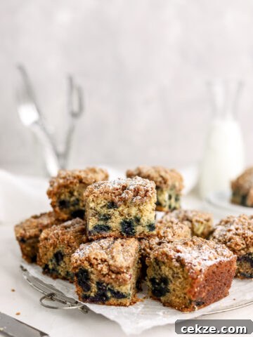 Squares of blueberry cake stacked on a rack.