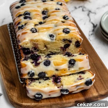 A blueberry loaf cake cut into slices and a lemon.