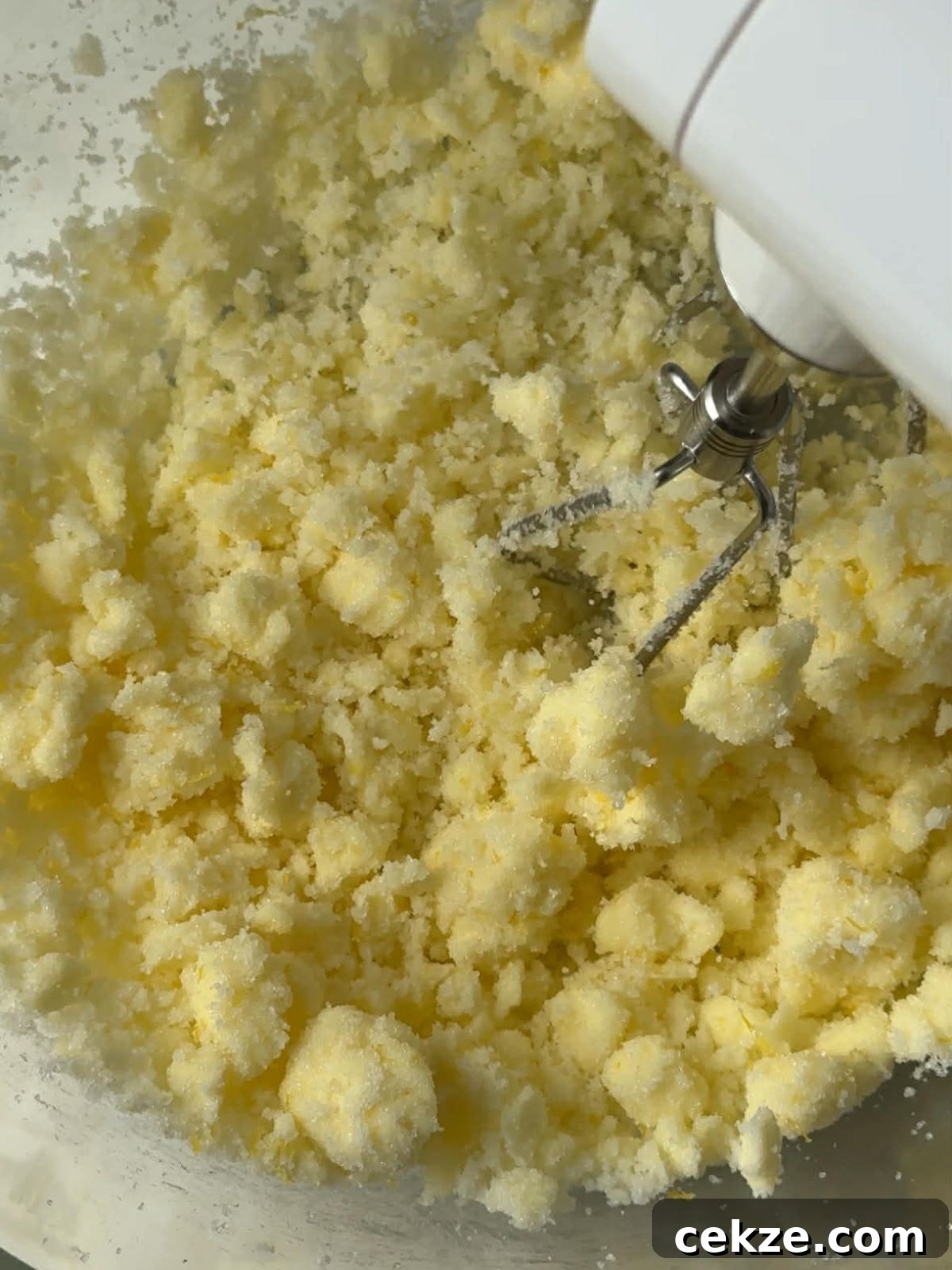 Butter and sugar being mixed with an electric mixer.