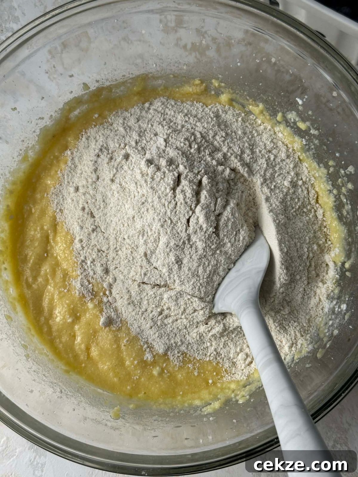 Stirring flour into cake batter in a bowl.