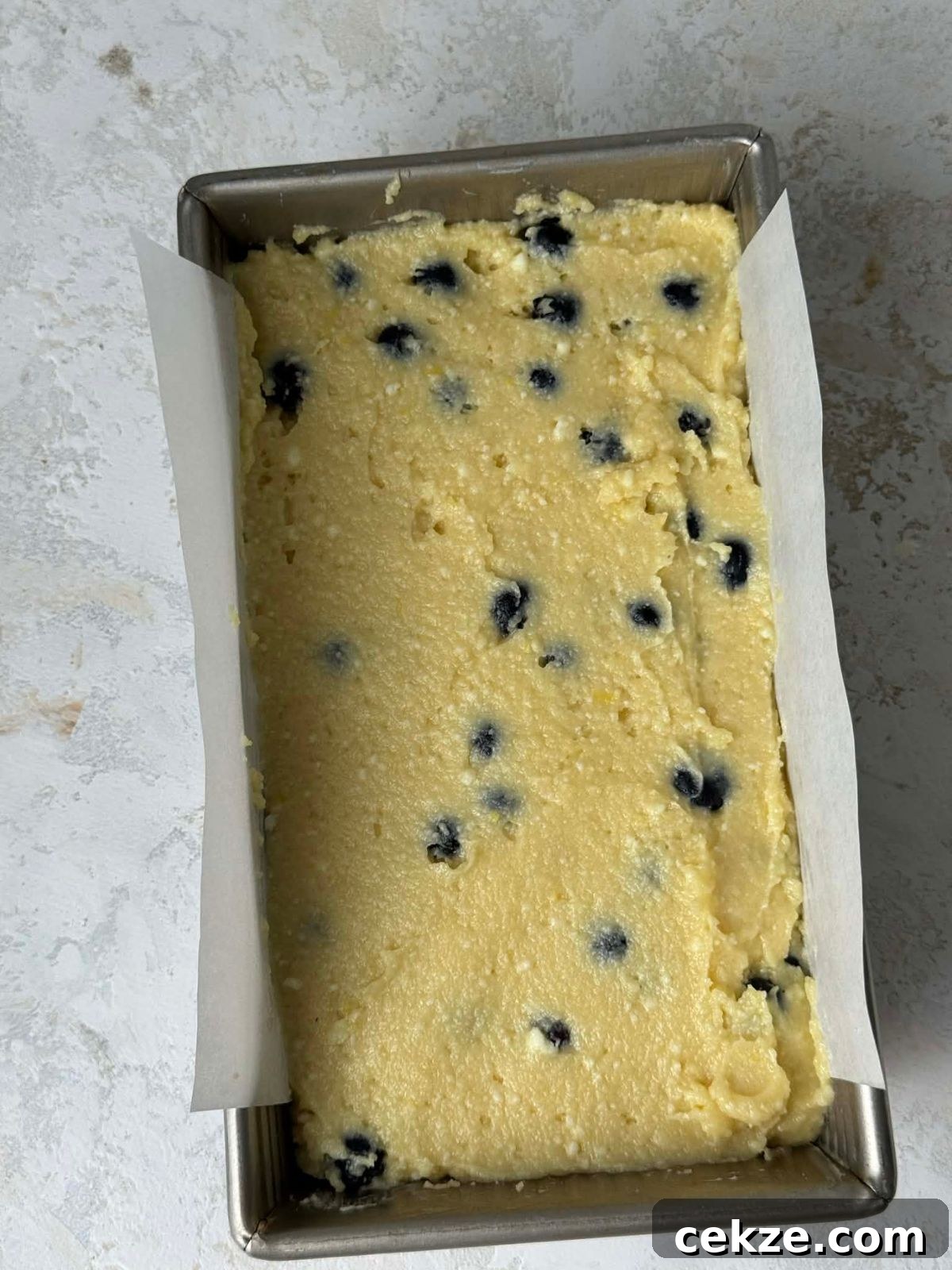 Blueberry filled loaf cake batter in a loaf pan.