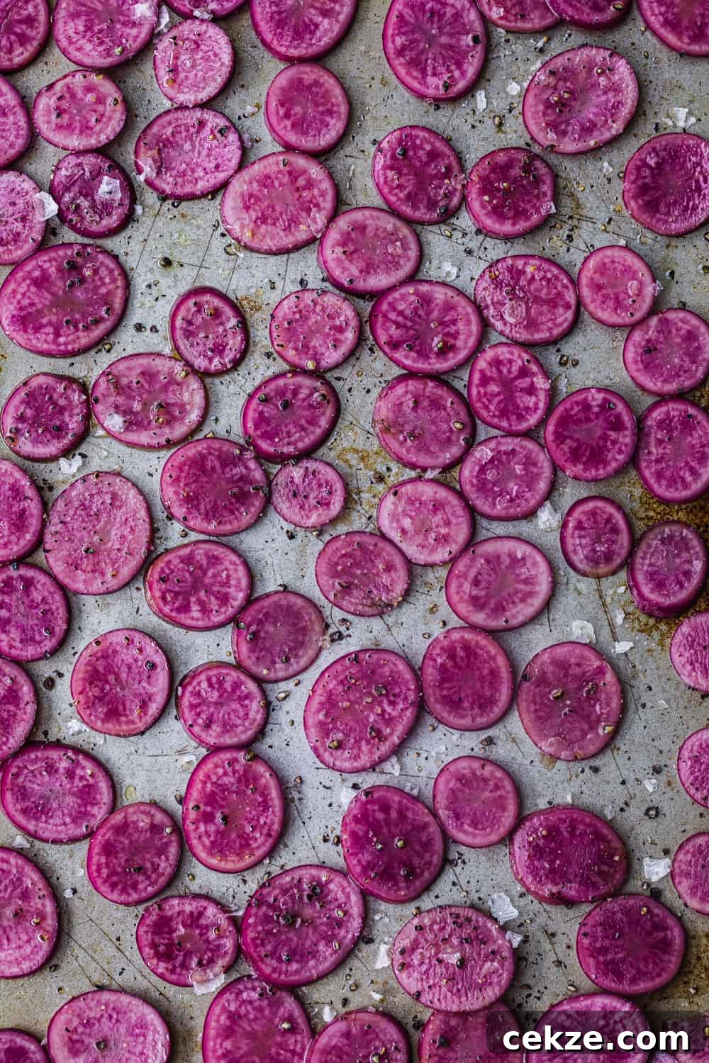 up close shot of pink potatoes thinly sliced on a cookie sheet with olive oil, salt and pepper to be used in the farmers market salad