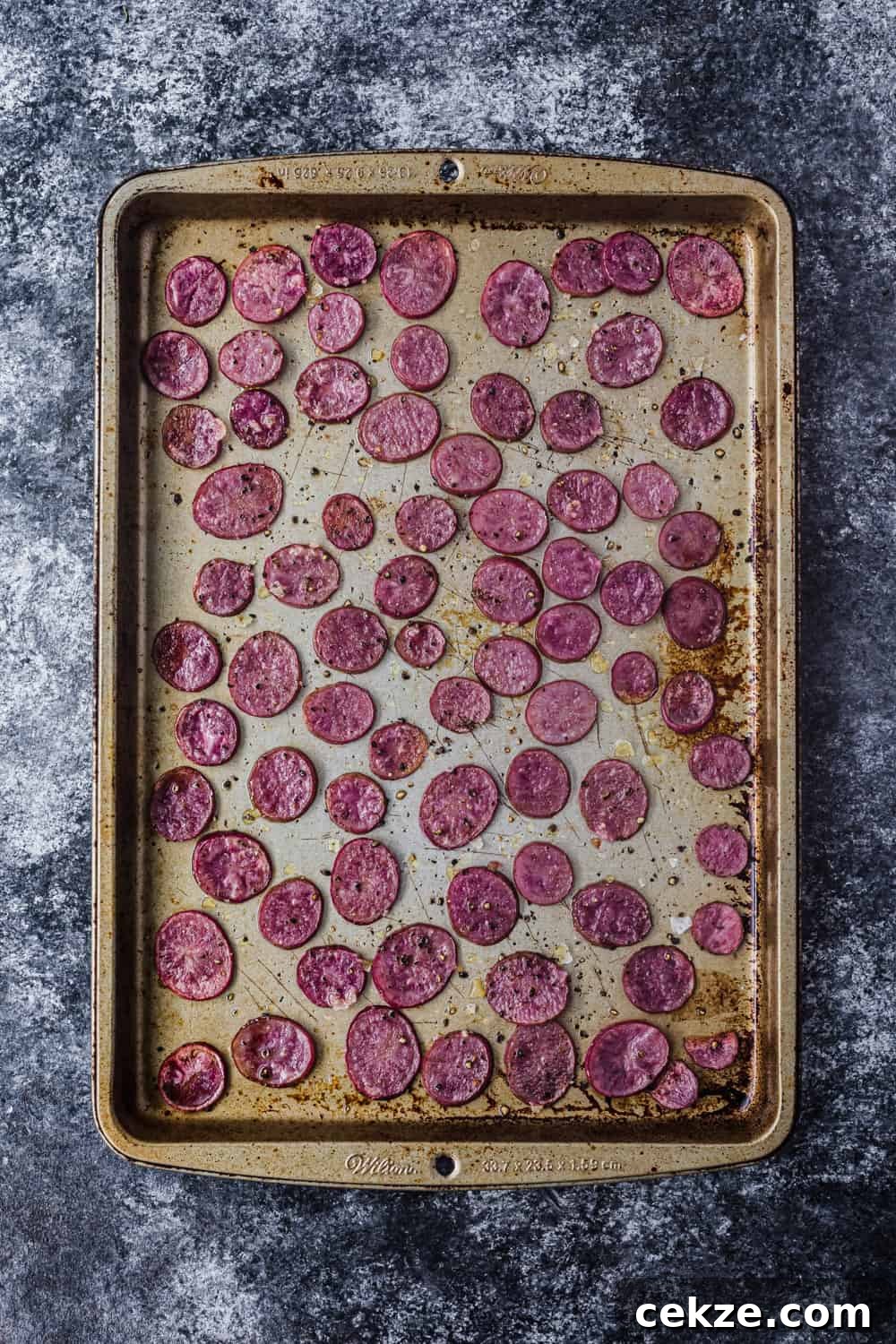 Overhead shot of a baking sheet with thinly sliced roasted pink potatoes, to be used in the farmers market salad