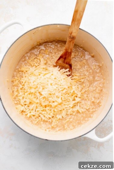 a pot of rice with cheese and a wooden spoon.