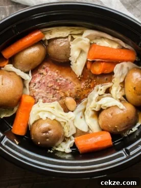 corned beer, cabbage, carrots, and potatoes in slow cooker.