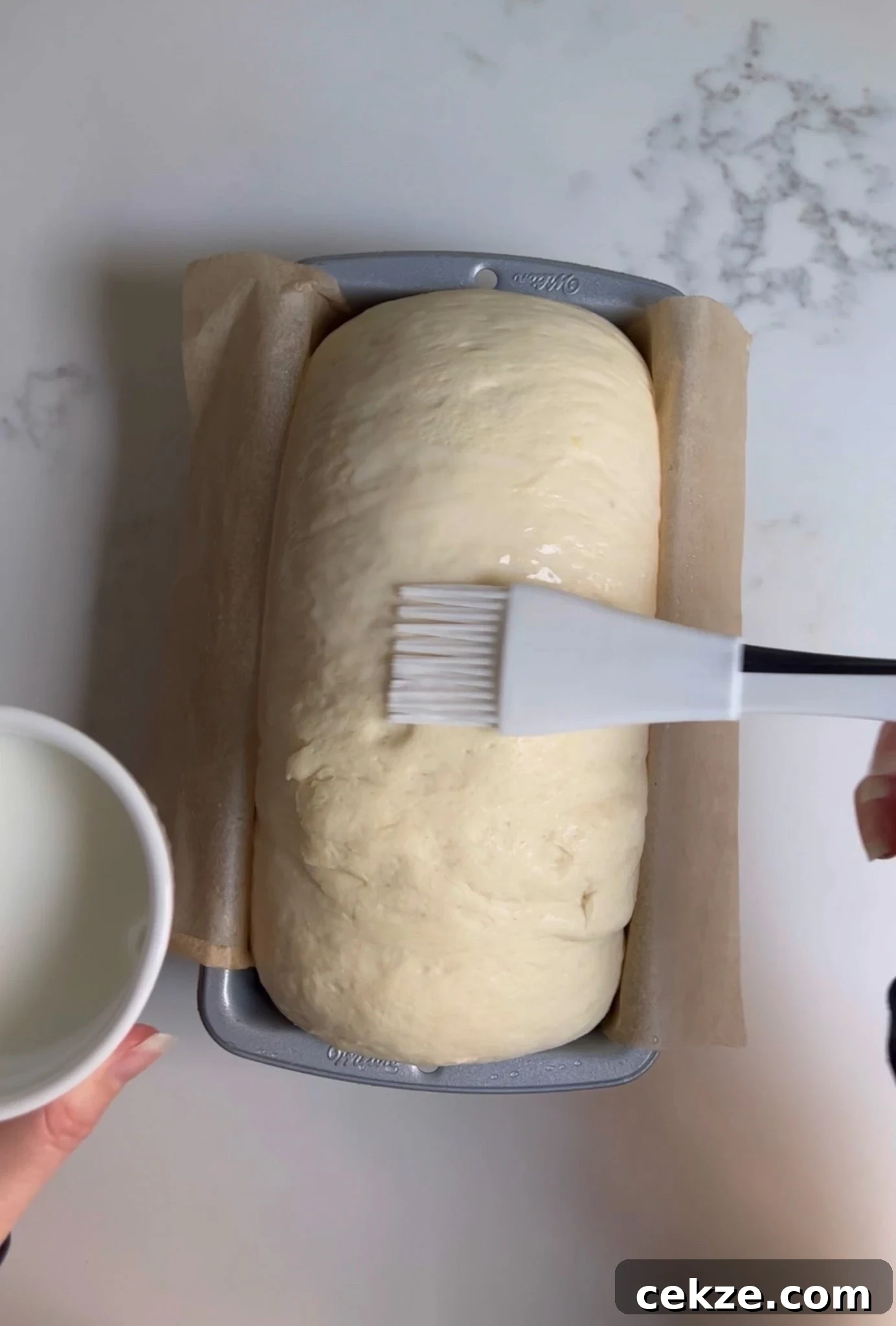 Brushing milk onto the loaf.