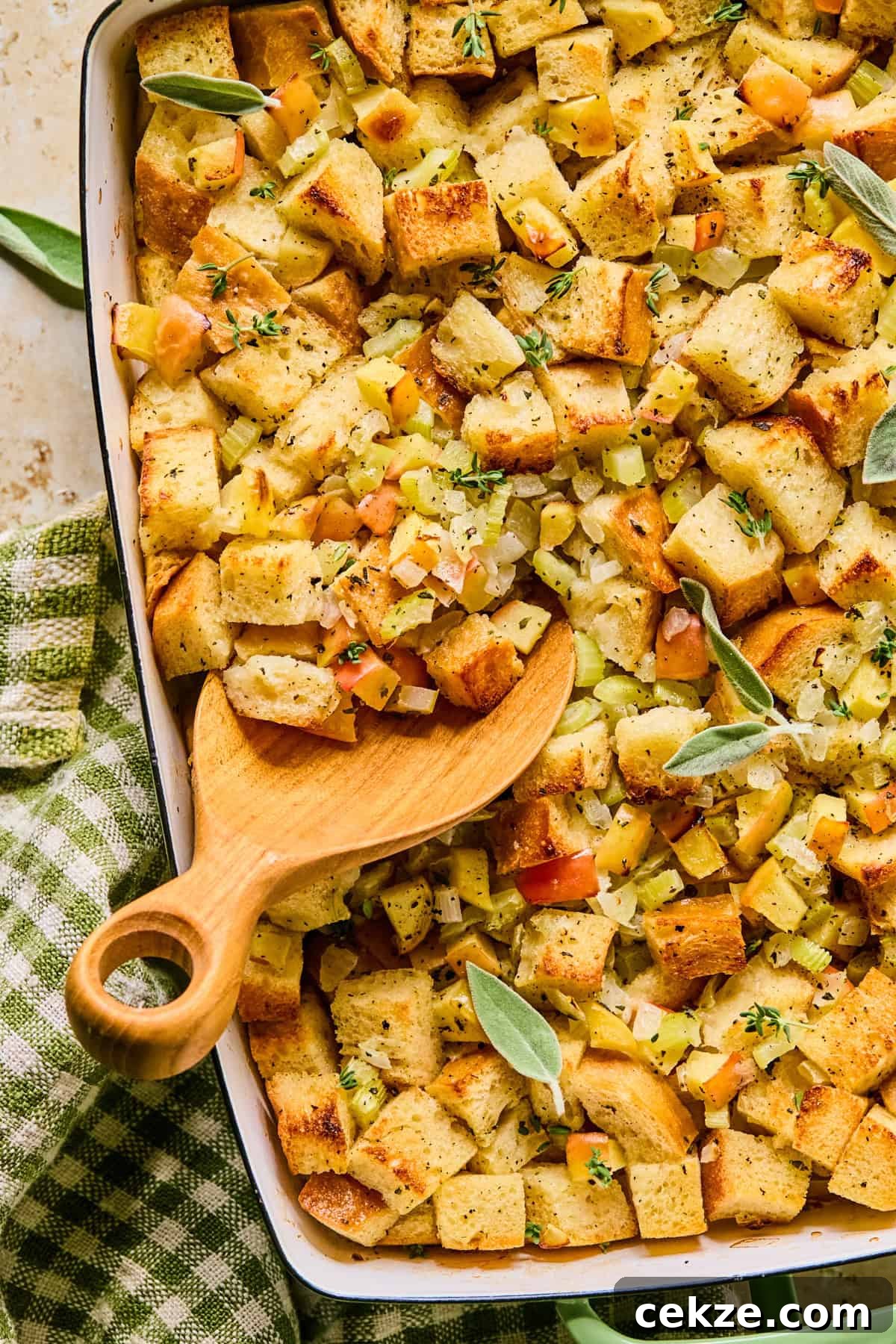 Apple and Sage Stuffing Recipe with Crispy Herbs 13 Pan with apple stuffing topped with freshly chopped parsley and spoon scooping into the dish.