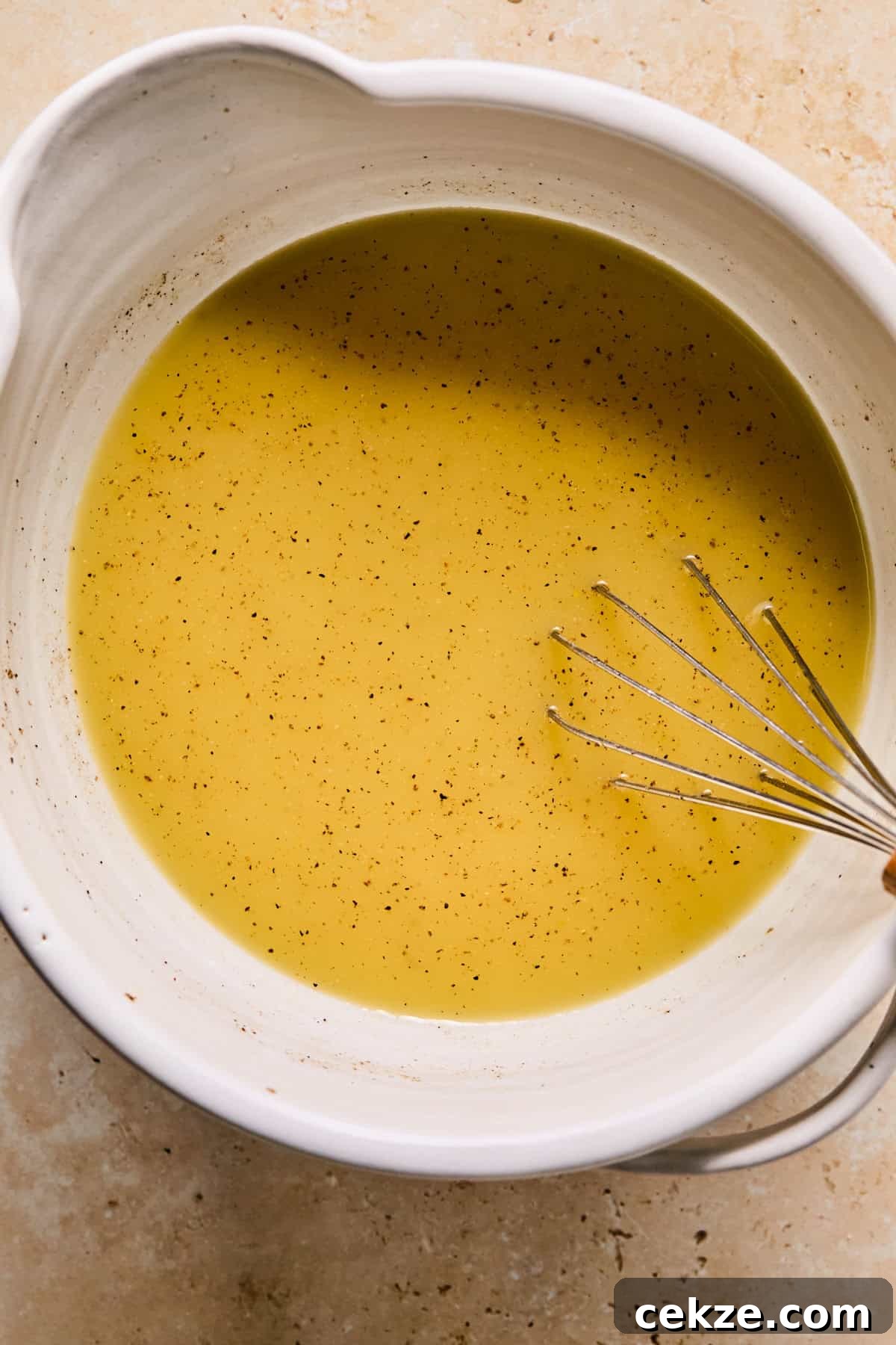 Apple and Sage Stuffing Recipe with Crispy Herbs 8 Whisked broth and egg mixture in bowl with whisk.