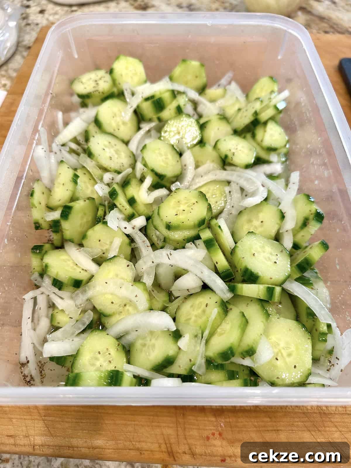 Crisp Quick Refrigerator Pickled Cucumbers in 30 Minutes 10 Quick pickled cucumbers and onions in a container with brine added.