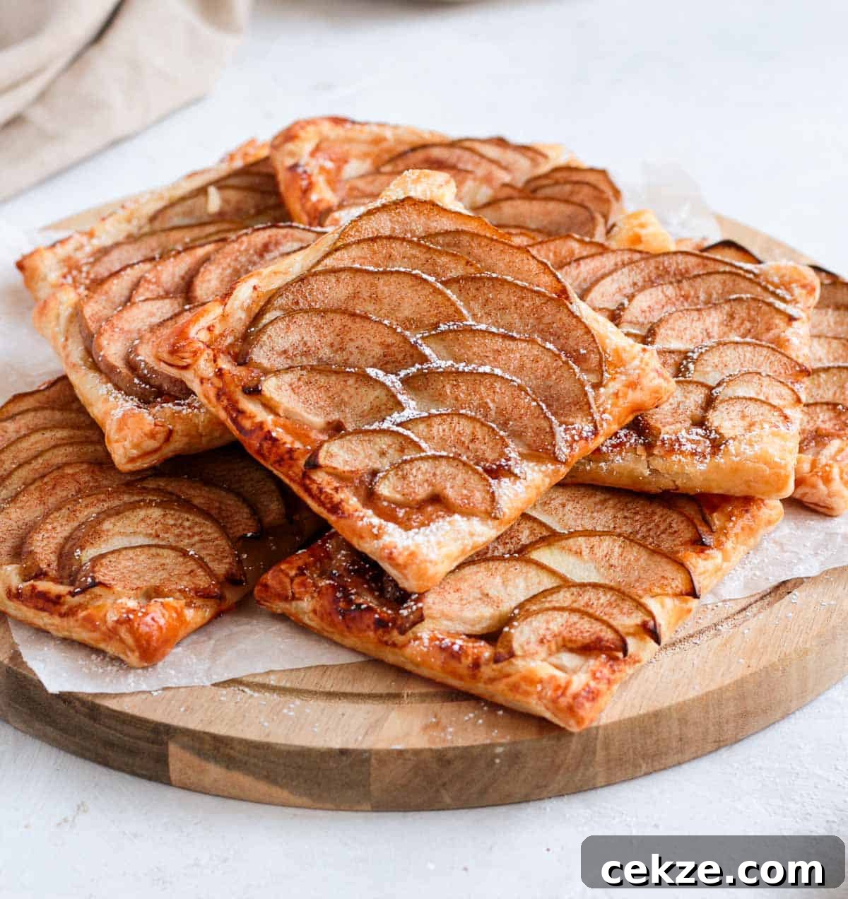 Puff Pastry Pear Tartlets with Honey and Almonds 4 Stack of tarts on a round wooden board.