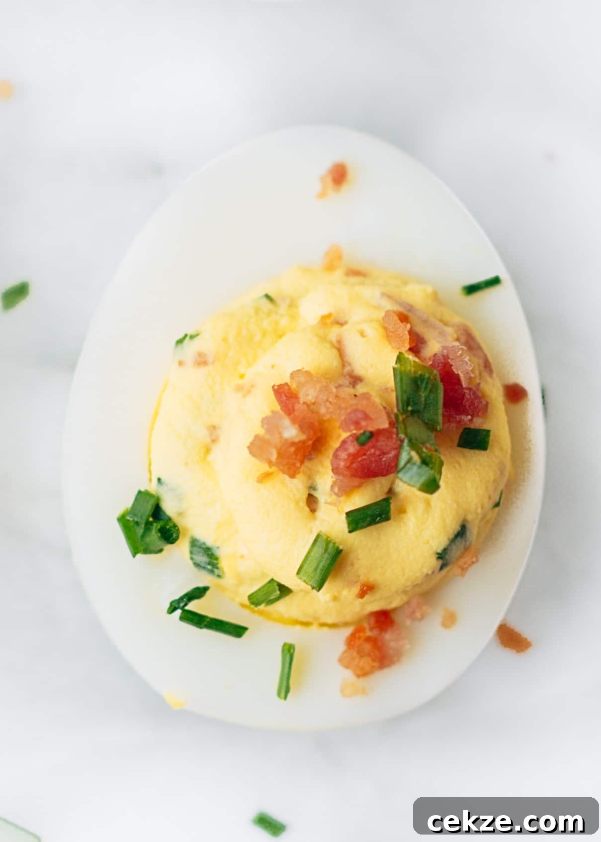bacon deviled egg with horseradish and chives on a marble board