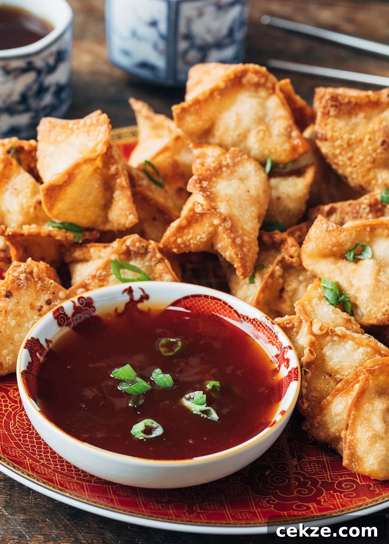 deep fried crab rangoon puffs on a plate with sweet and sour dipping sauce