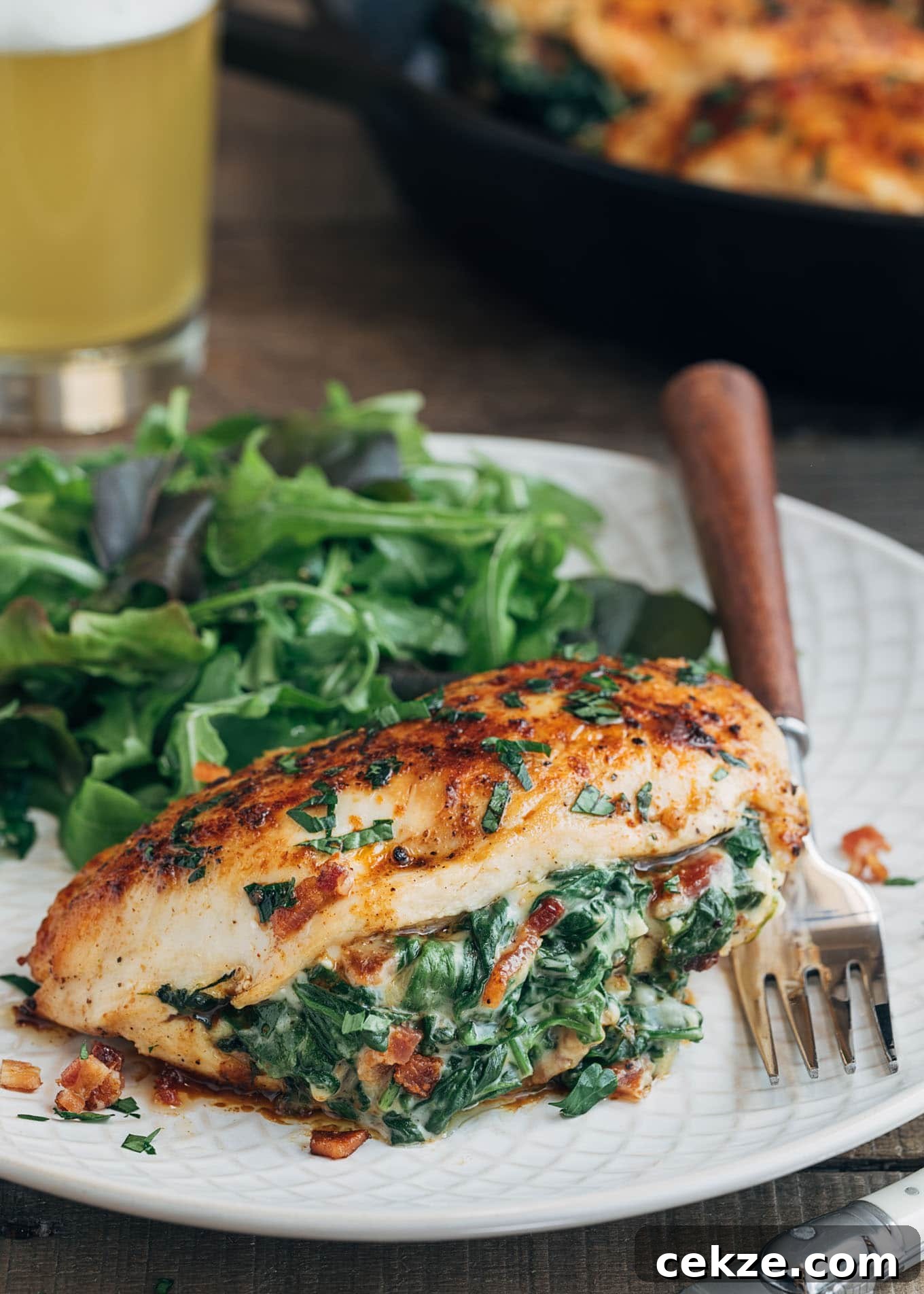 spinach stuffed chicken breast on an ivory plate with salad greens
