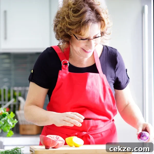 Instant Pot Zereshk Polo — Persian Barberry Rice Recipe 16 Beth Lee in red apron looking at vegetables on cutting board