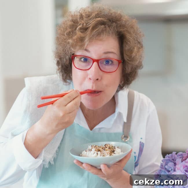 Instant Pot Zereshk Polo — Persian Barberry Rice Recipe 17 Beth Lee holding red chopsticks and eating rice out of blue bowl.