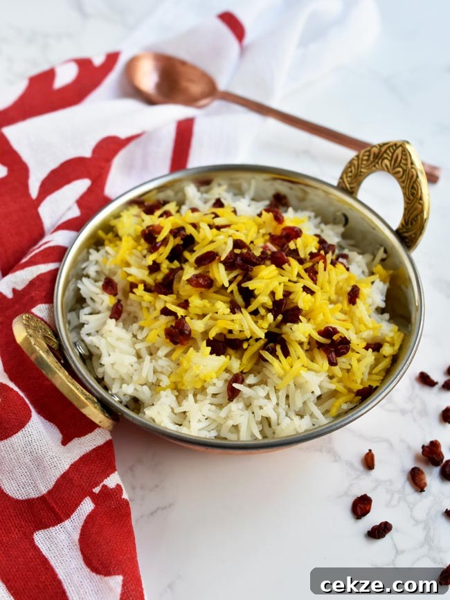 Instant Pot Zereshk Polo — Persian Barberry Rice Recipe 5 Saffron barberry rice in copper bowl with pomegranate napkin and copper spoon.