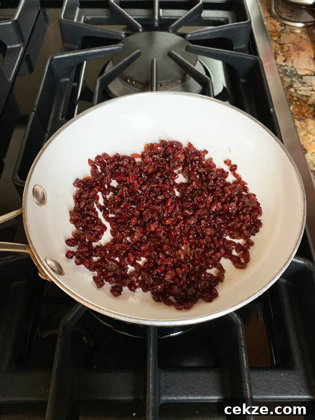 Instant Pot Zereshk Polo — Persian Barberry Rice Recipe 9 Barberries sautéing in white fry pan on stovetop.