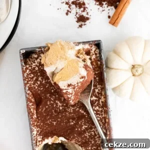 pumpkin tiramisu in a loaf pan with a spoon and a white pumpkin on the side.
