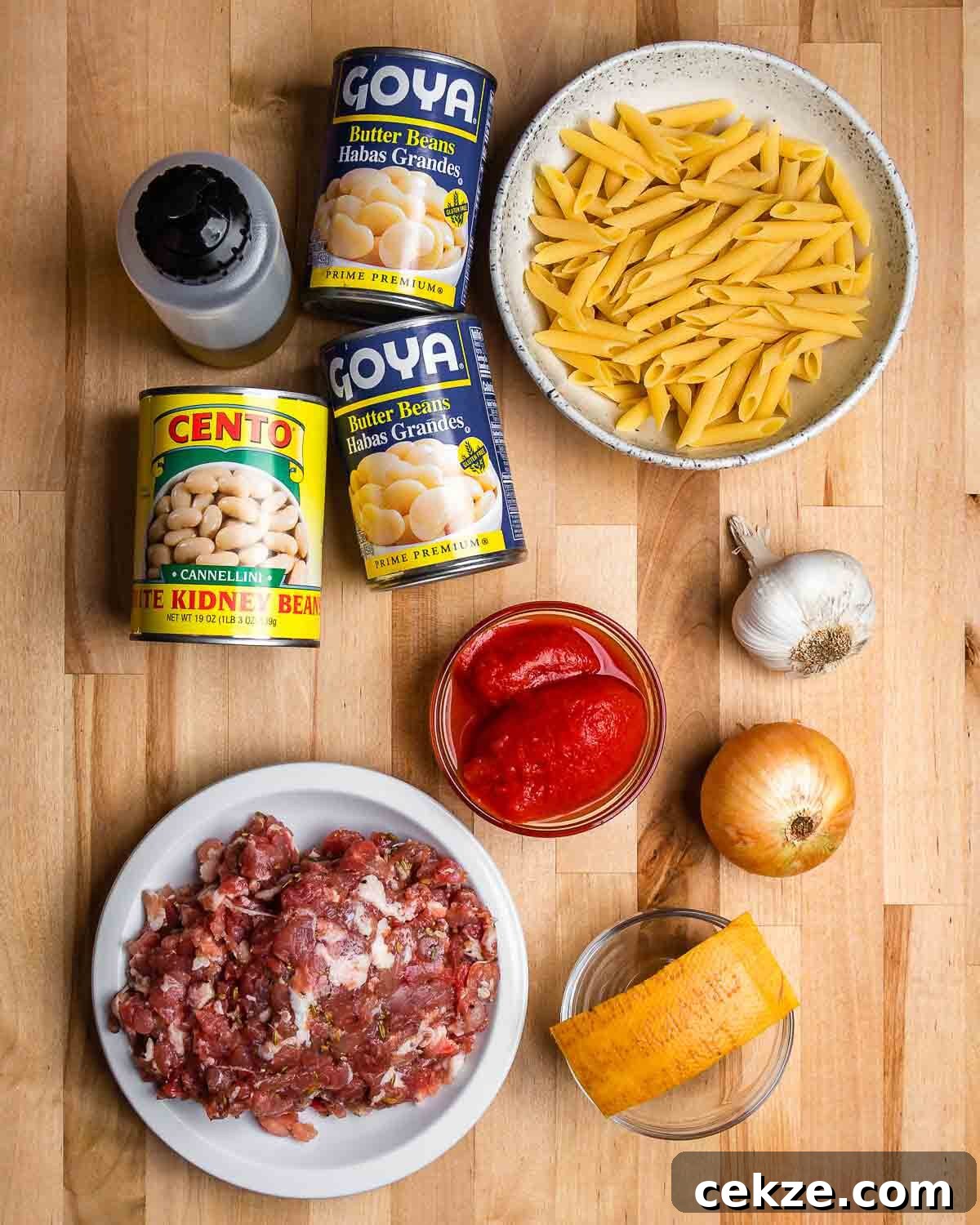 Ingredients shown: olive oil, beans, penne, tomatoes, bulk Italian sausage, Parmigiano rind, onion, and garlic.