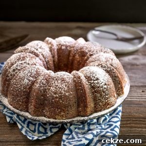 Authentic Cuban Rum Cake Recipe: Moist Drunken Cake with Rum Glaze 12 Sideview of a Cuban Rum Bundt Cake dusted with powdered sugar on a serving platter. Hostess At Heart