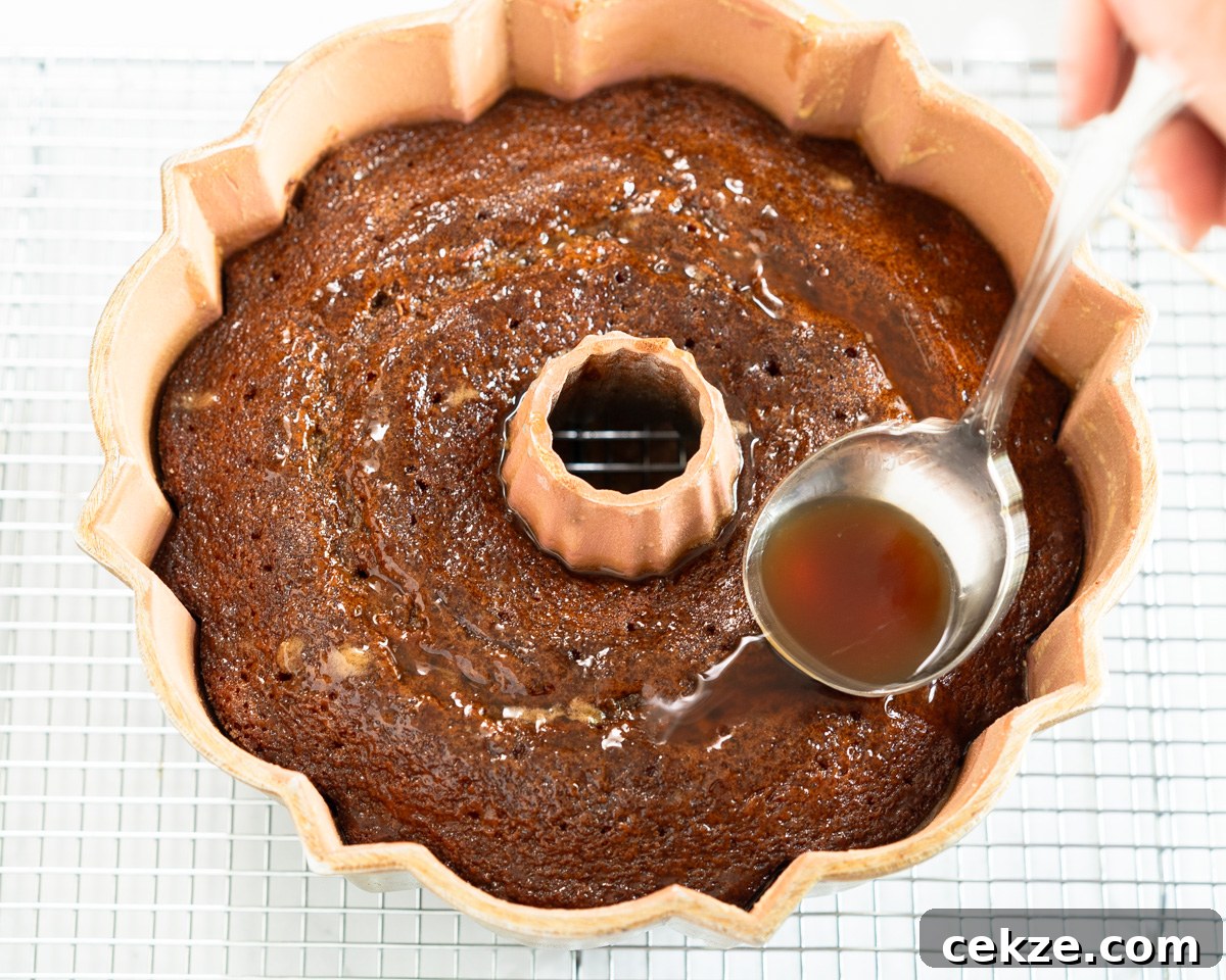 Authentic Cuban Rum Cake Recipe: Moist Drunken Cake with Rum Glaze 8 Top down view rum syrup being spooned into a cake poked with holes. Hostess At Heart