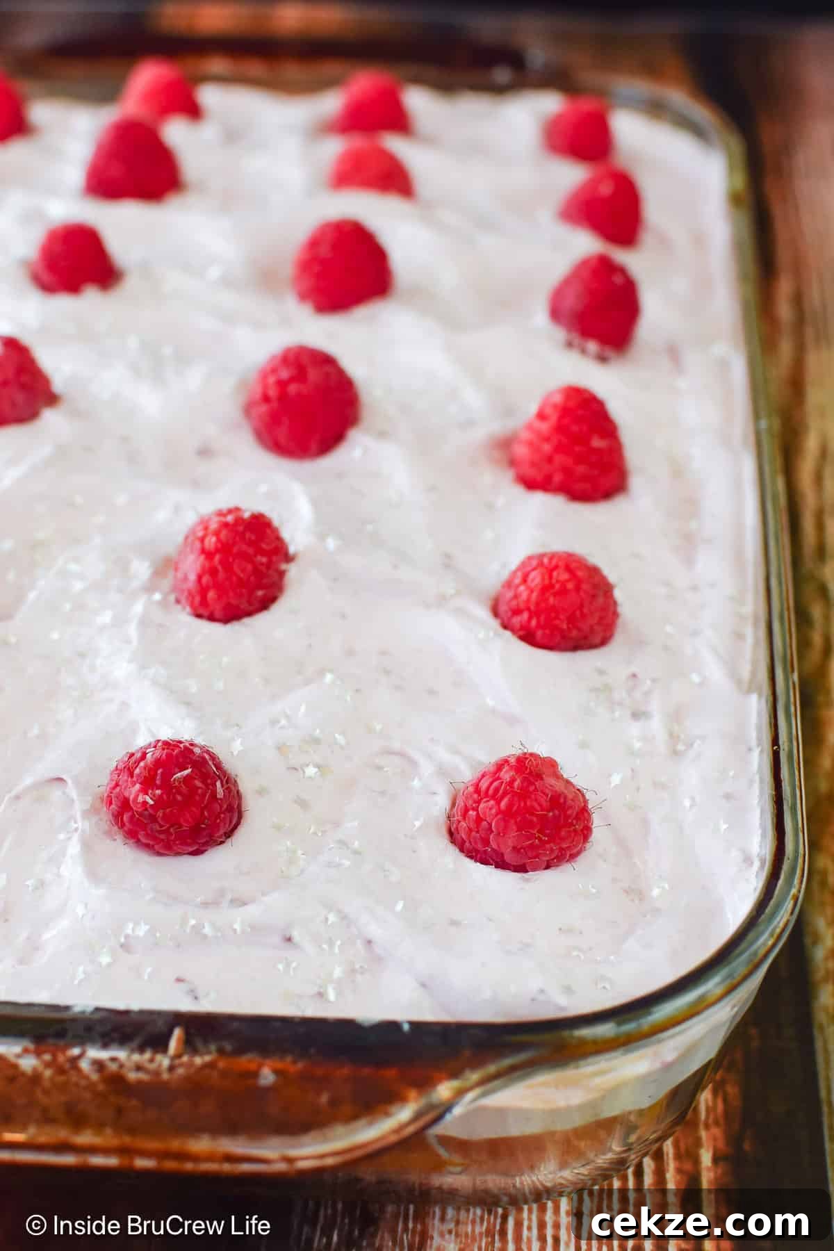 A frosted raspberry poke cake in a glass pan.