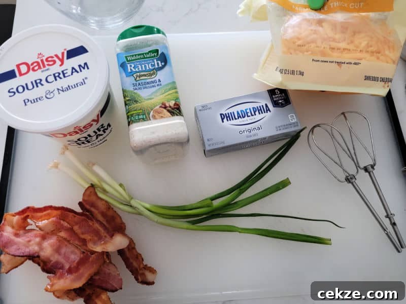 Creamy Bacon Cheddar Ranch Dip Recipe for Parties and Game Day 3 Sour cream, ranch dressing mix, cream cheese, cheddar cheese, bacon slices, and green onions on a cutting board