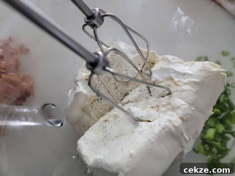 Creamy Bacon Cheddar Ranch Dip Recipe for Parties and Game Day 4 Mixer beaters in a glass bowl with cream cheese, ranch dressing mix, and green onions