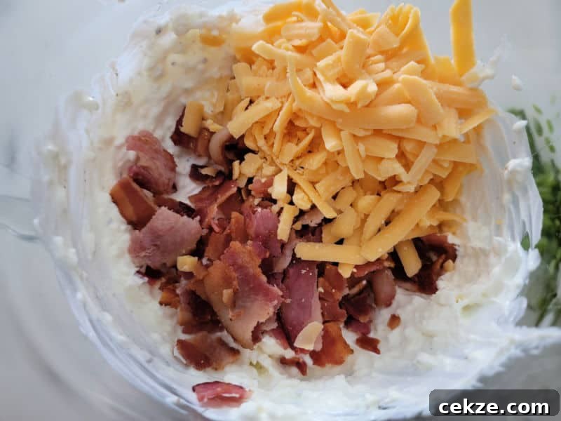 Creamy Bacon Cheddar Ranch Dip Recipe for Parties and Game Day 5 cheddar cheese and bacon pieces on sour cream mix in a glass bowl