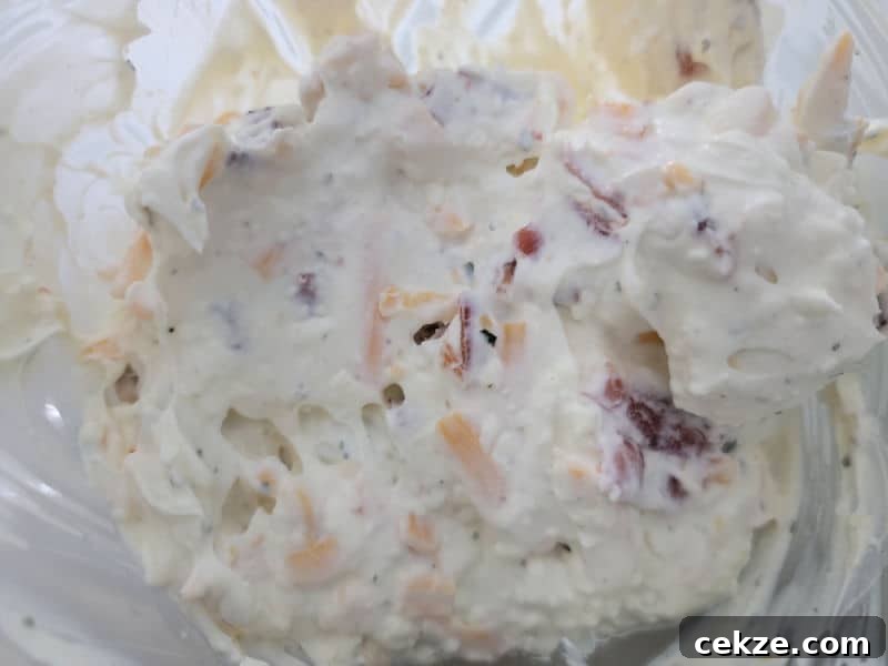 Creamy Bacon Cheddar Ranch Dip Recipe for Parties and Game Day 6 sour cream ranch dip with shredded cheese in a glass bowl mixed together.
