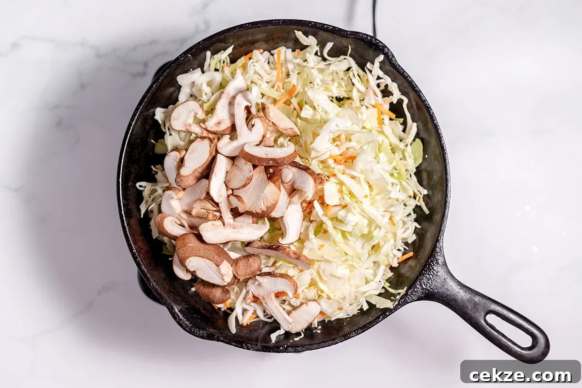 Coleslaw mix and shiitake mushrooms in a cast iron skillet.