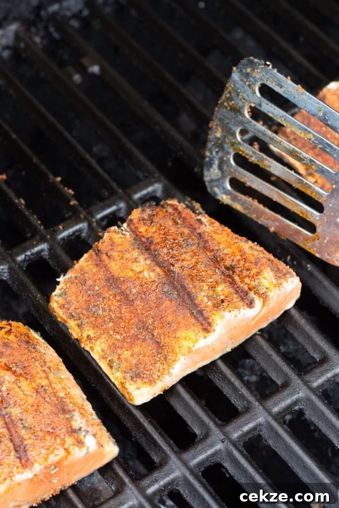 15-Minute Chili Lime Grilled Salmon Recipe 8 Close up of salmon filets on a grill being flipped to skin side up with a metal spatula.
