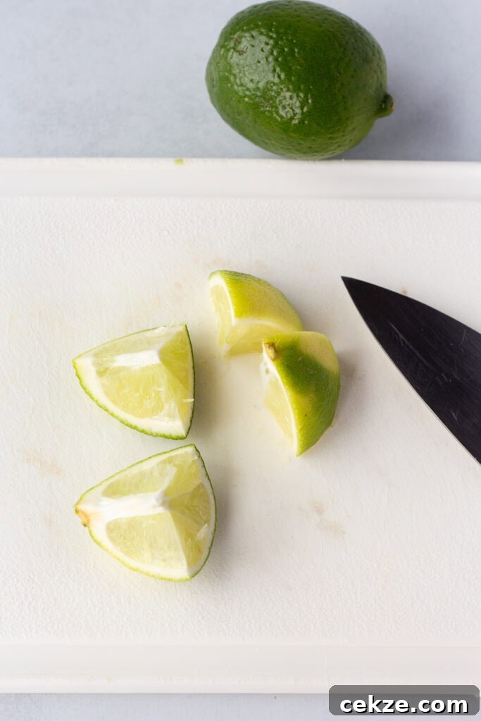 15-Minute Chili Lime Grilled Salmon Recipe 10 Half a lime cut into four pieces resting on a white cutting board. A large sharp knife rests on the cutting board as well, and a whole lime is next to the cutting board.