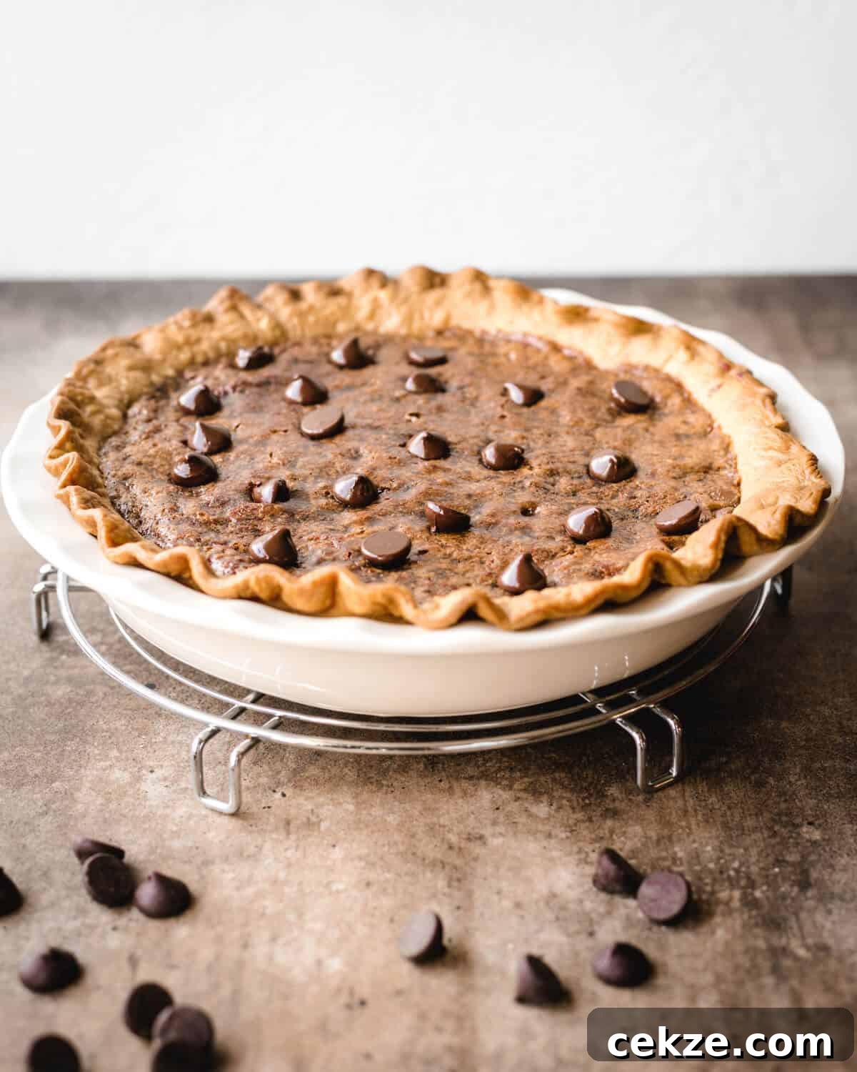 Ultimate Chocolate Chip Cookie Pie Recipe for Every Occasion 4 A chocolate chip pie sitting on a cooling rack with chocolate chips sprinkled in front of the pie plate.
