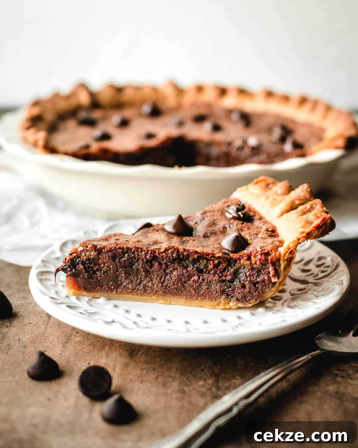 Ultimate Chocolate Chip Cookie Pie Recipe for Every Occasion 9 Slice of chocolate chip pie on a dessert plate in front of the remaining pie.