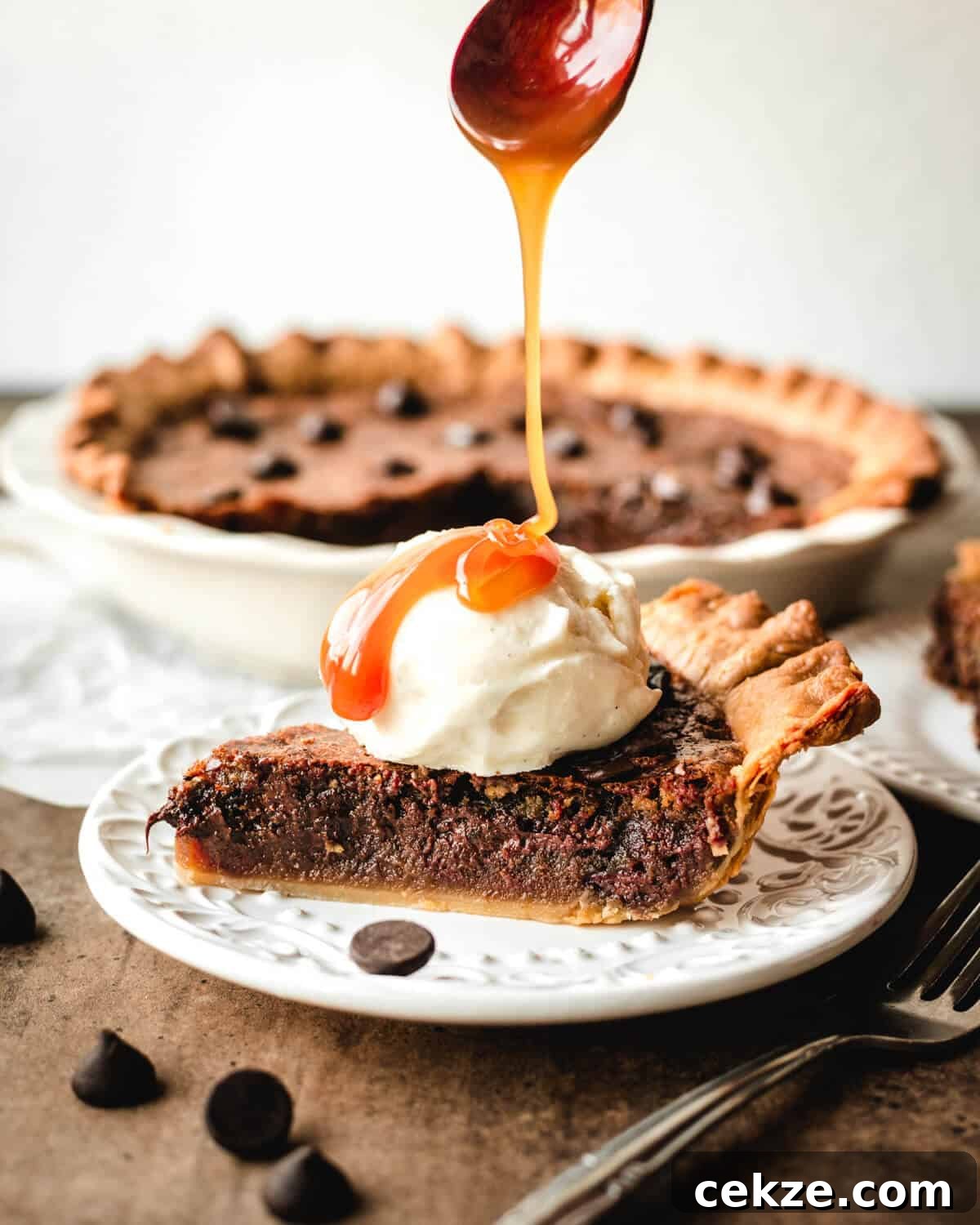 Ultimate Chocolate Chip Cookie Pie Recipe for Every Occasion 10 Caramel drizzling off a wooden spoon onto a scoop of ice cream sitting on a slice of chocolate chip pie.
