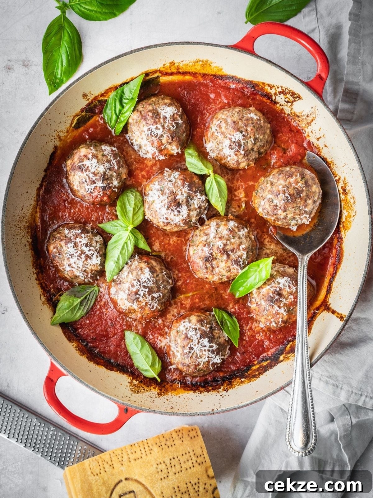 Juicy Italian Meatballs Without Breadcrumbs — Recipe & Tips 2 Italian Meatballs simmering in marinara, garnished with fresh basil and Parmesan.
