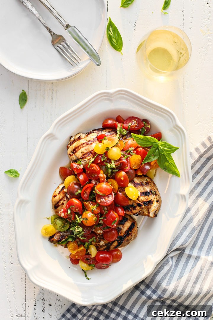 grilled bruschetta chicken on a white platter next to a glass of wine and fresh basil