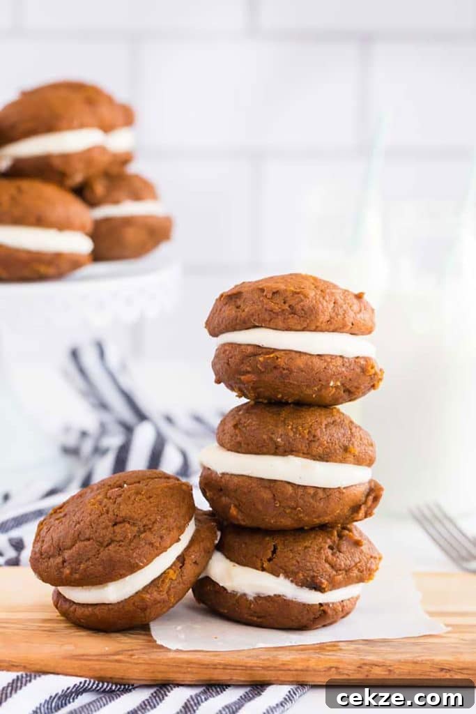 Pumpkin whoopie cookies stack up on a wooden board.