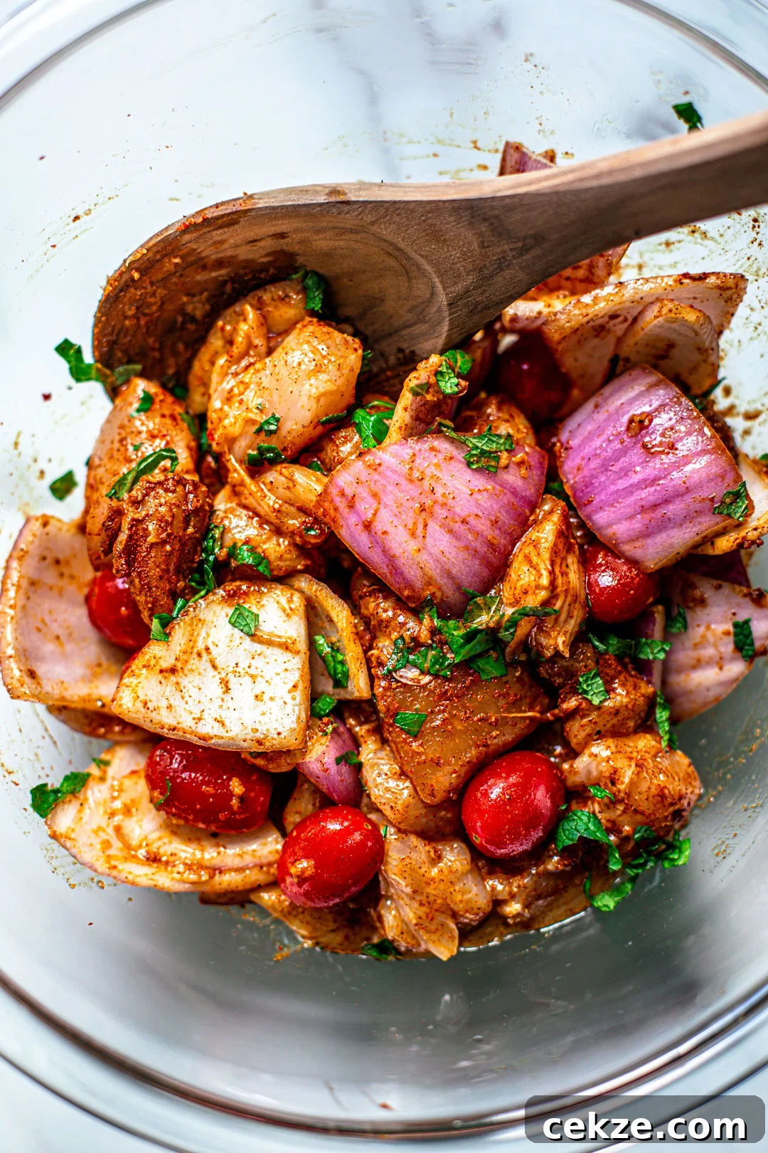 Bowl of raw chicken and vegetables, seasoned with Moroccan seasoning.