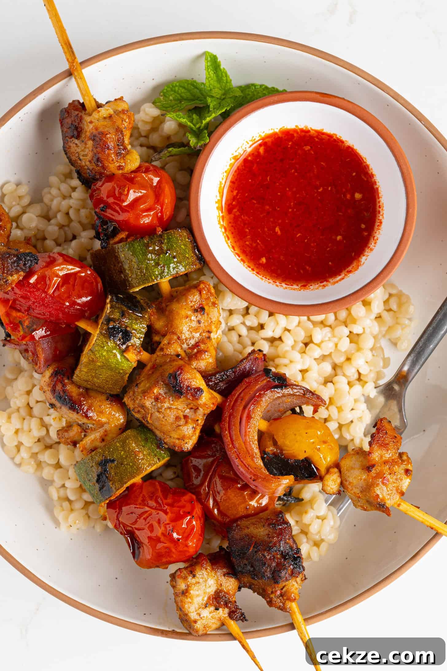 harissa chicken skewers on a plate of couscous