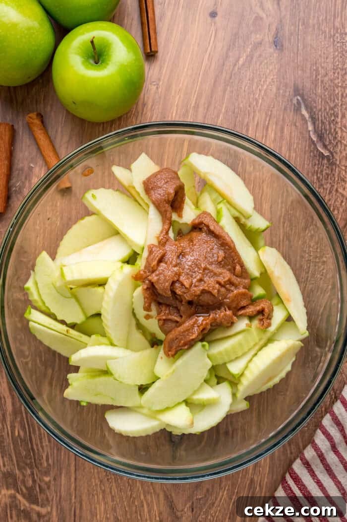 Granny Smith apple slices are tossed with sugar and spices then baked until tender in this Baked Apples recipe. Serve with ice cream. Apple slices and spices in a bowl