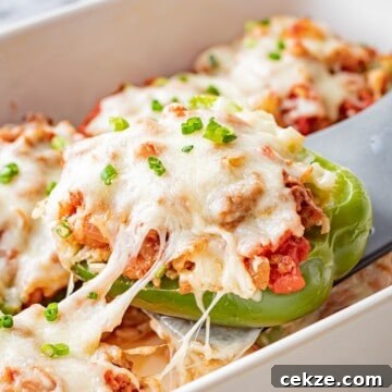 Baked ground beef stuffed pepper with melted cheese over white pan.