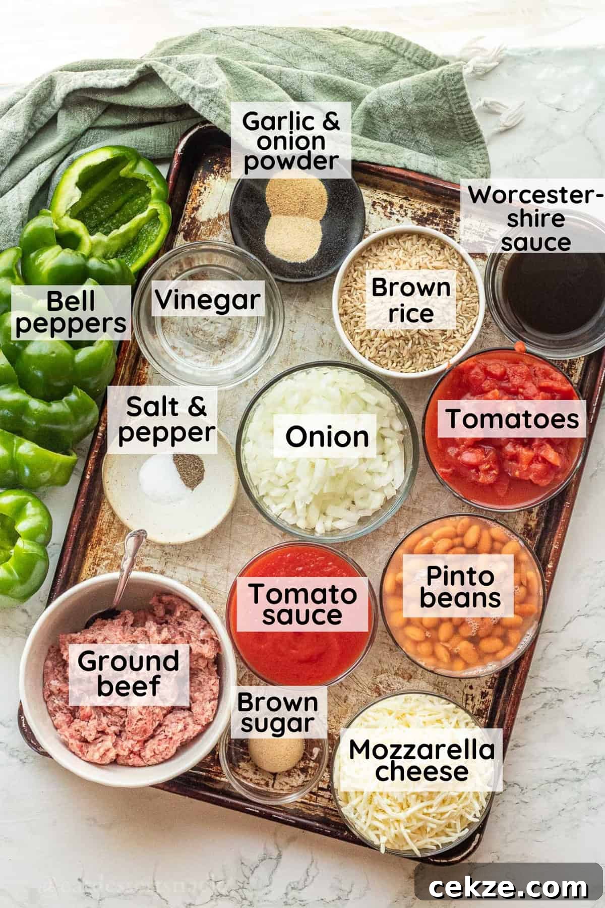Labeled Ingredients for ground beef stuffed bell peppers in glass dishes on metal pan.