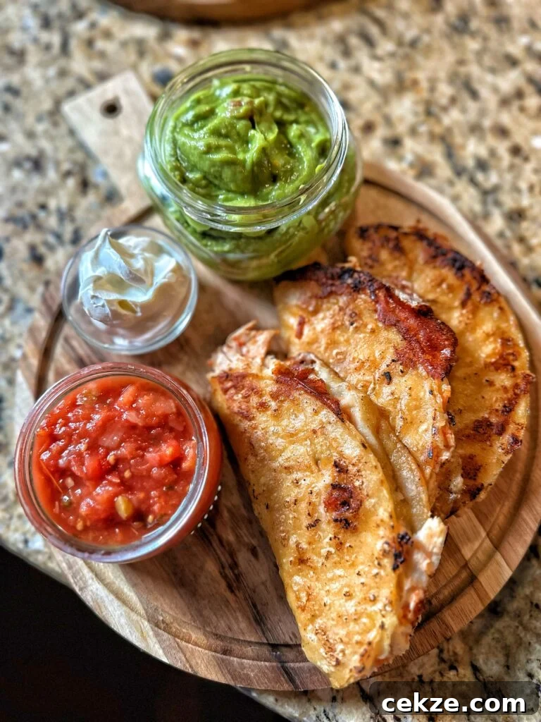 Crispy Chicken Tacos next to salsa, sour cream, and guacamole 