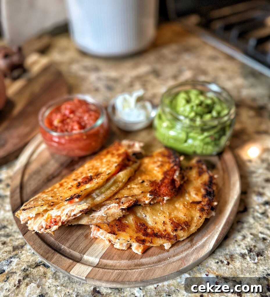 Crispy chicken tacos in front of salsa, sour cream, and guacamole 