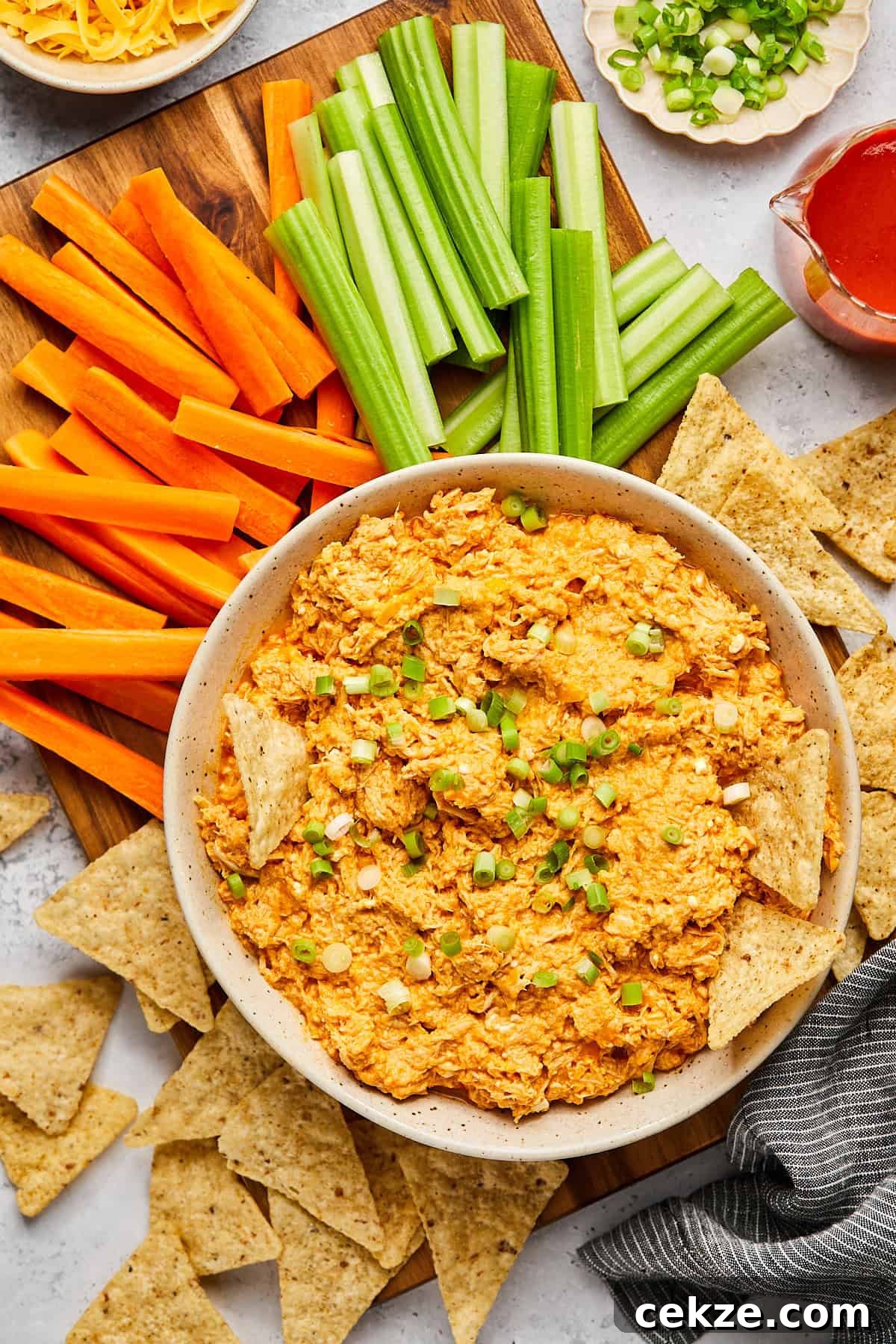 a bowl of high protein buffalo chicken dip surrounded by tortilla chips and veggies. 